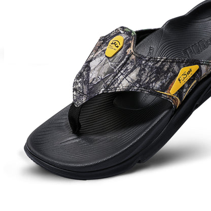 A single flip-flop from PCSsole, featuring a black textured sole and footbed, a camouflage-patterned upper strap.